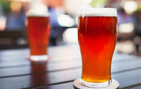 Pint glass of craft beer indian pale ale on wooden table in beer gardenの写真素材