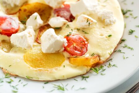 Delicious omelette with tomato, potato and goat or greek feta cheeseの写真素材