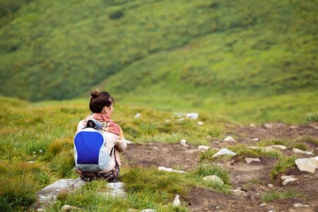 Young girl having a rest during her hike in mountains. Woman sitting on a rock and enjoying natureの写真素材
