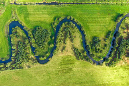 Aerial photograph of winding river in rural landscape. Small river winding in green grass fieldの写真素材