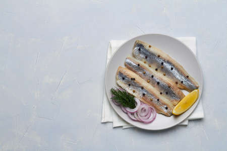 salted fillet of herring decorated with dill pepper lemon red onionの写真素材