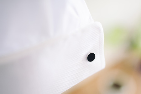 A groom fastening a cuff-link before getting marriedの写真素材