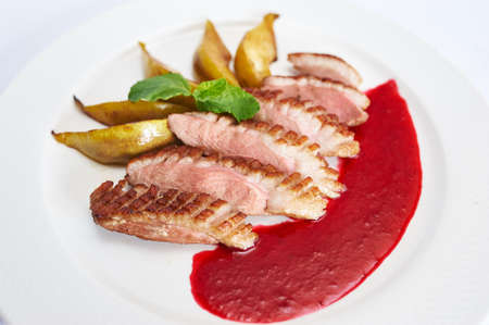 Duck breast with raspberry sauce on white plate studio shotの写真素材