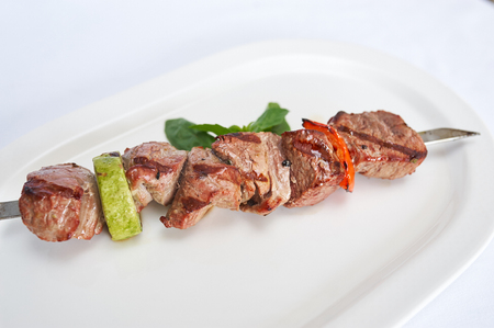 Skewers of beef on white plate studio shotの写真素材
