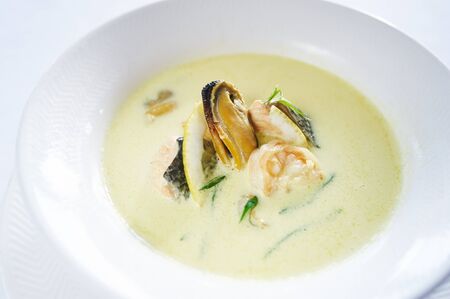 Saffron soup with seafood on white plate studio shotの写真素材