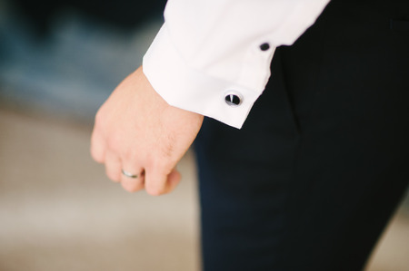 A groom fastening a cuff-link before getting married