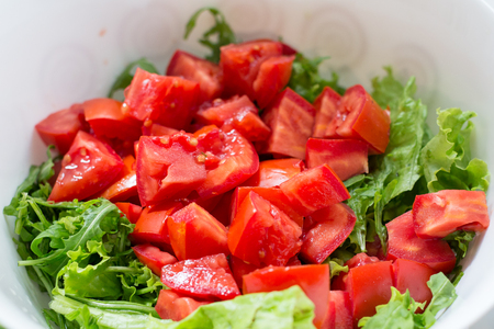 Healthy green salad, tomatoes in white bowlの写真素材