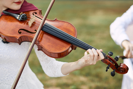 Violinist woman. Young woman playing a violin outside.の写真素材