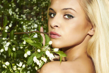 Beautiful blond woman in green forest  flowersの写真素材