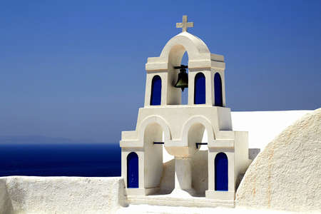 Bell tower above the beautiful blue bay at Santoriniの写真素材