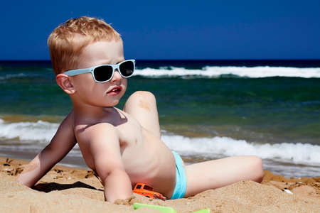 Child sitting on the beach in sand  little boy near the seaの写真素材