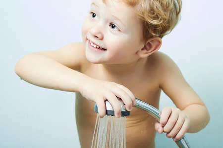 smiling little boy is bathed in the showerの写真素材