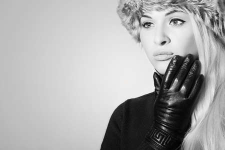 Monochrome portrait of Young Woman in Fur Hat. Beautiful Blond Girl in Black Leather Gloves. Winter Fashion Beautyの写真素材