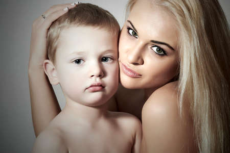 Young Mother Hugging Child. Beautiful Blond Woman with Little Son. Happy Beautiful Familyの写真素材