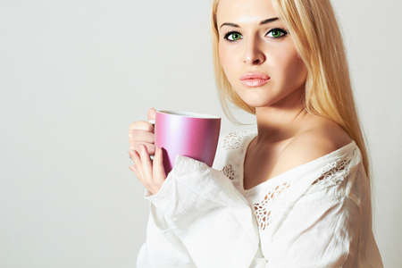 Beautiful blond woman drinking Coffee. Cup of tea. Hot drink. Sweet girl in the Morningの写真素材