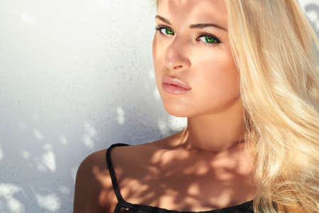 beautiful blond woman in daylight. real shadows on the face.girl near white wall. top modelの写真素材