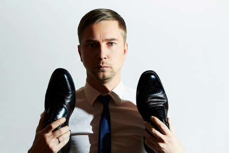 fashion portrait of handsome man holds shoes.Businessman in tieの写真素材