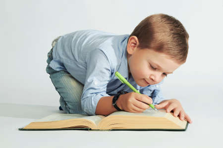 education and school concept.little boy with book on the floor. funny child writerの写真素材