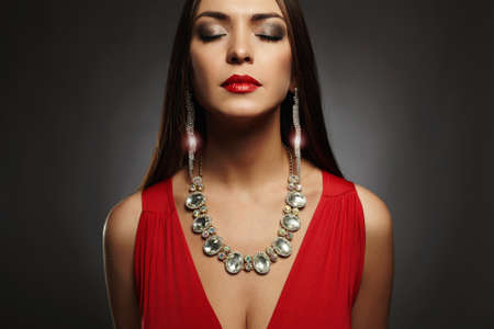 fashion portrait of young beautiful sexy woman.Beauty girl wearing jewelry.elegant lady in red dressの写真素材