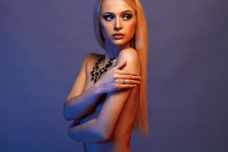 sexual beautiful blond girl in jewelry.fashion art photo of elegant nude model in the light colored spotlightsの写真素材