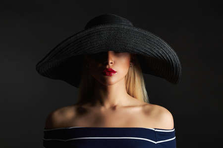 Beautiful woman in hat. Retro fashion beauty model girl with red lipsの写真素材