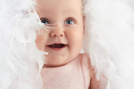 smiling baby girl in feathers. little funny child.newbornの写真素材