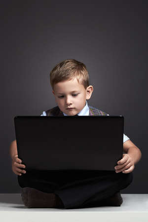 boy with computer. funny child looking in notebook. education technologyの写真素材