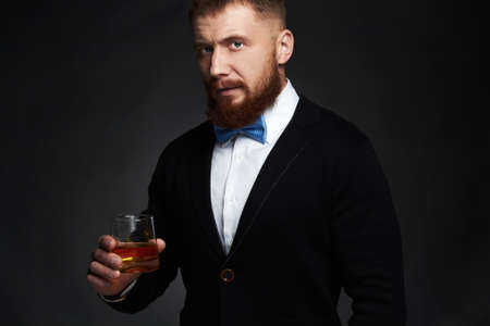 stylish handsome bearded man enjoying whiskey.Elegant man drinking alcoholの写真素材