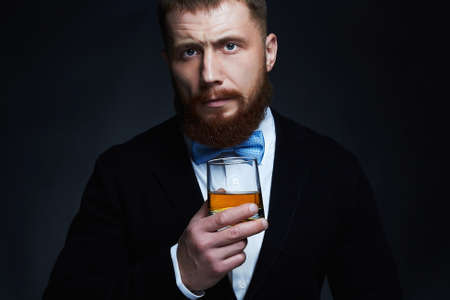 stylish handsome bearded man enjoying whiskey.Elegant man drinking alcoholの写真素材
