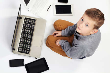 fashionable child with computers, tablets, phones, gadgets around. little boy and new technologyの写真素材