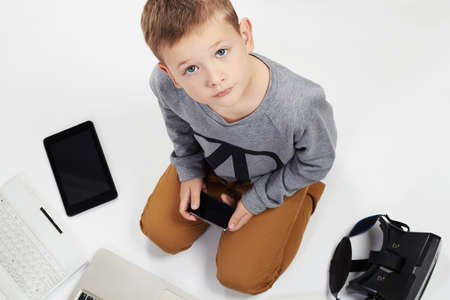 fashionable child with computers, tablets, phones, gadgets around. little boy and new technologyの写真素材