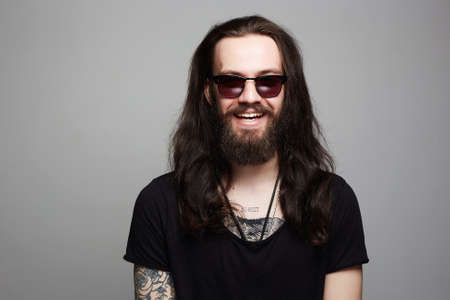 Smiling Hipster boy in sunglasses.handsome bearded man with tattooの写真素材