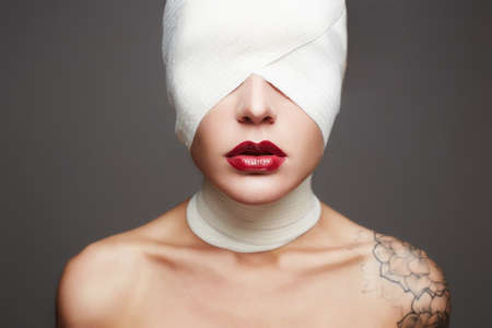 halloween mask.female face wrapped in bandage.beautiful girls lips.beauty make-up woman with tattooの写真素材