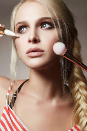 Beautiful woman face. Make-up artist applies cosmetics. model blonde girlの写真素材