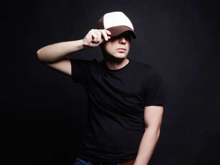 Young Man in Cap. Fashionable Hipster Boy in hat over black Backgroundの写真素材