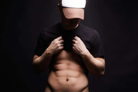 Young Man with Beautiful Body. Stylish Boy in Hat show his Musclesの写真素材