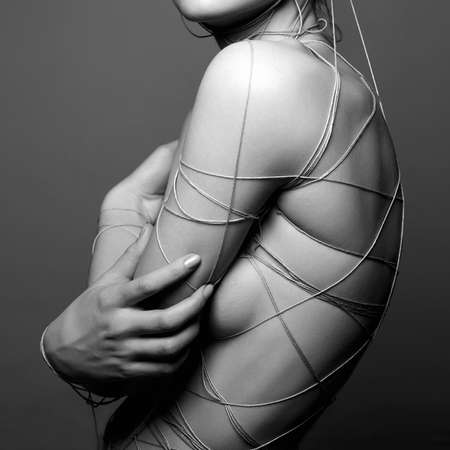 Black and White Fashion portrait. Beautiful young Woman with thread on the face and Bodyの写真素材