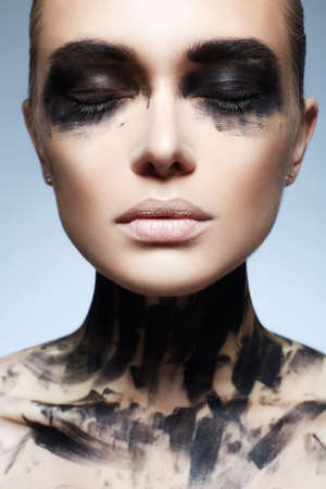 Beautiful Young woman with Paint Face. paint over a face and Body. Girl in Black Paintの写真素材
