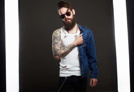 fashionable handsome man with tattoo and sunglasses. Hipster bearded Stylish boy in jeans and glassesの写真素材