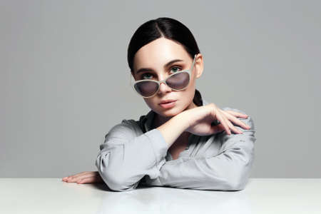 beautiful young woman in glasses sits at table. Beauty Teacher girl