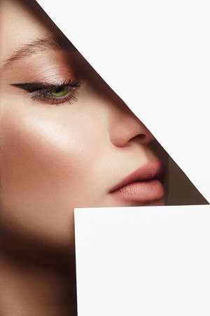young beautiful woman with makeup into paper hole. make-up artist concept. arrows on the eyes. number oneの写真素材