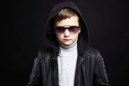 fashionable little boy in hoodie and sunglasses. stylish kid in leather coatの写真素材