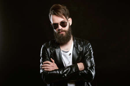 fashionable handsome man in sunglasses. Brutal bearded Sexy boy in leather coatの写真素材