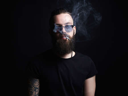 handsome smoking man. Hipster tattoed boy with cigarette. Brutal bearded man