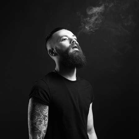 handsome bearded smoking man. Hipster tattoed boy with cigaretteの写真素材