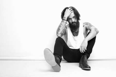 monochrome fashion portrait of handsome man in shoes.Brutal bearded boy with tattoo