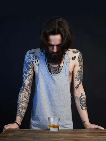 drunk man with beard and tattoo. man with glass of whiskey bearded hipster boy portrait