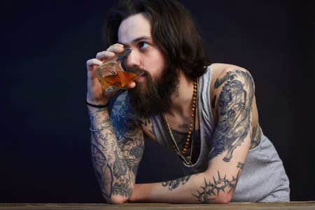 man with beard and tattoo. man drink whiskey. bearded hipster boy in Barの写真素材