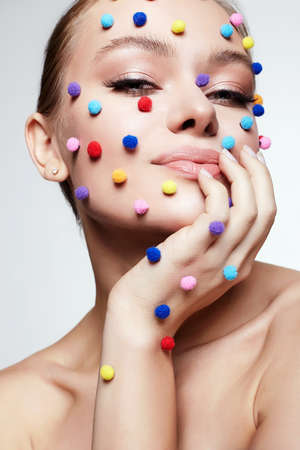 Beautiful young woman with unusual make-up. Beauty portrait of smiling girl with colored balls makeup. の写真素材