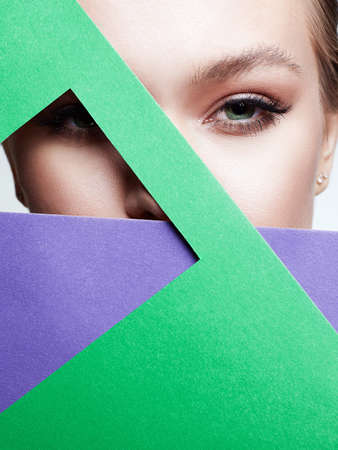 Beautiful young woman with green color paper. Beauty portrait of girl with make-upの写真素材